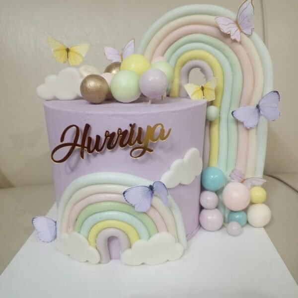 Purple pastel birthday cake with fondant rainbow, butterflies, and custom gold name topper.