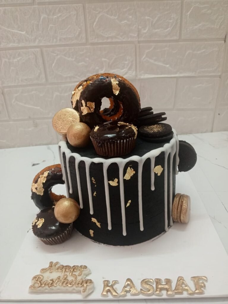 Custom black buttercream birthday cake for Kashaf, featuring white chocolate drip, gold leaf accents, chocolate donuts, macarons, and Oreo cookies.