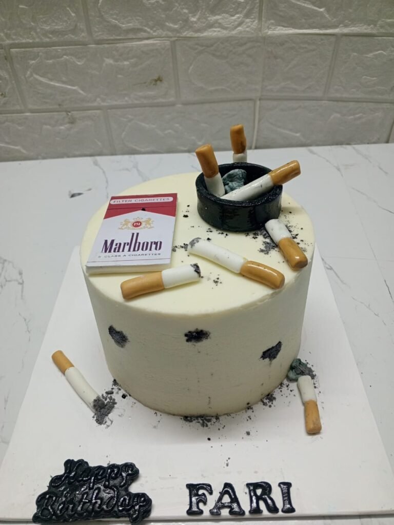 White cylindrical birthday cake featuring edible Marlboro cigarette pack, black ashtray, and cigarette butt decorations for "Fari" birthday.