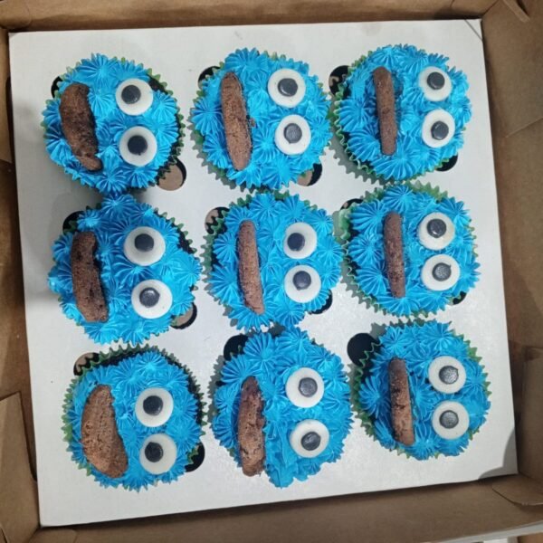 A box of nine blue Cookie Monster cupcakes with googly eyes and chocolate chip cookies.